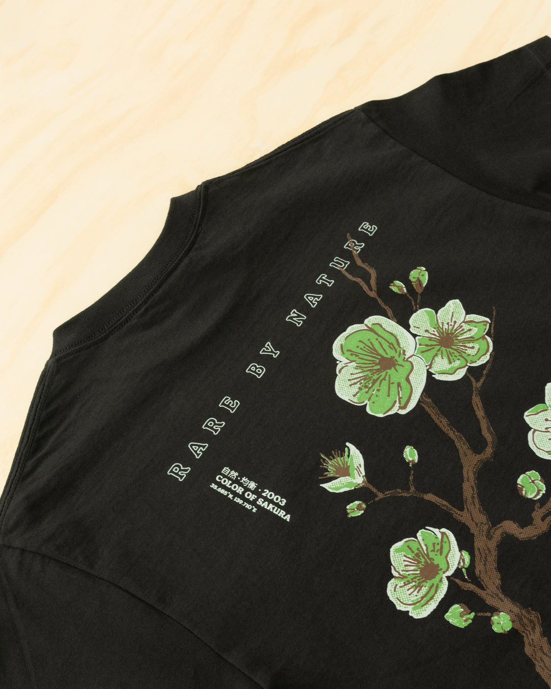 Green sakura branch in bloom, symbolizing rarity, growth, and natural balance. Acrylick Zen Capsule Tee.