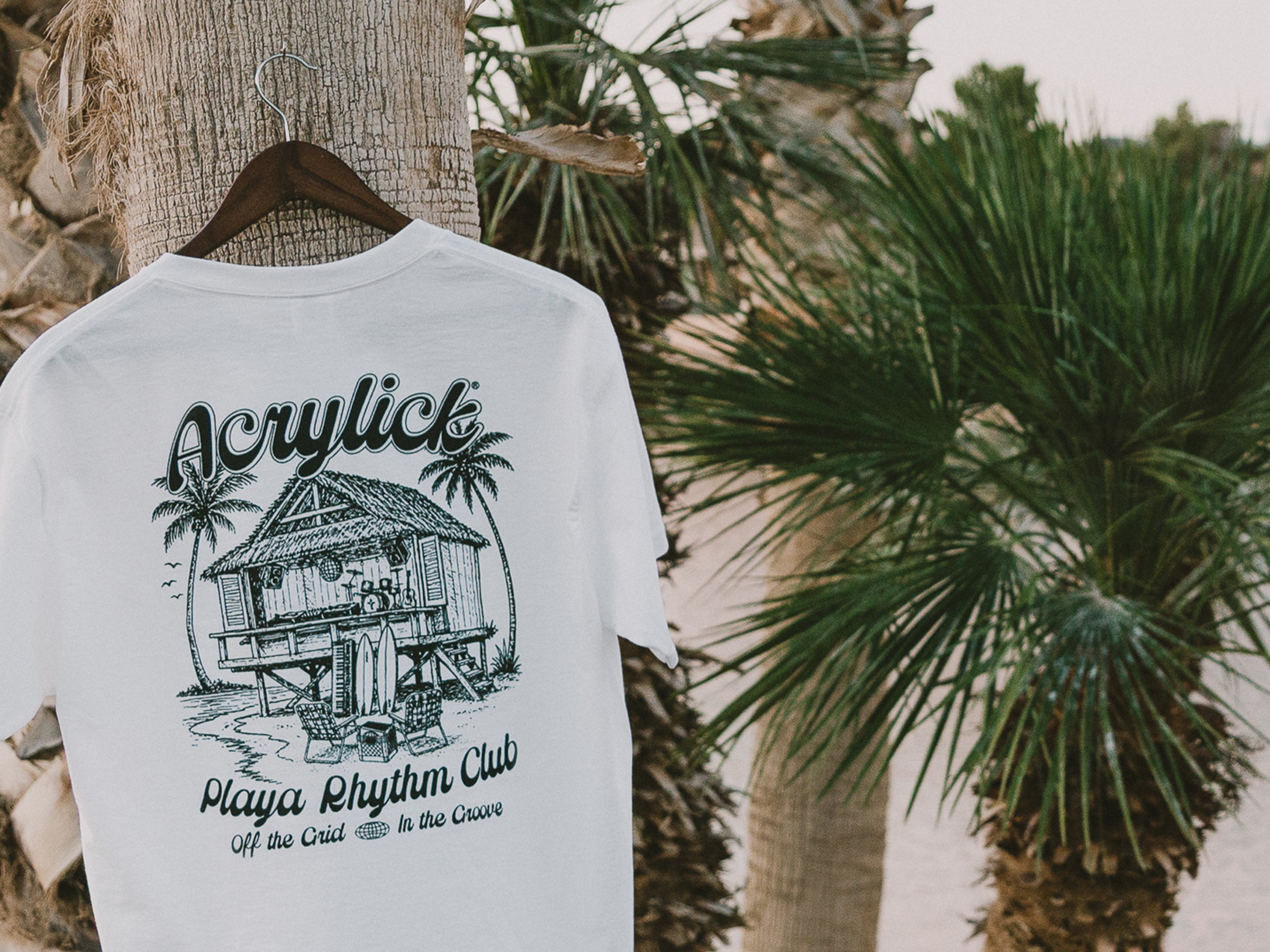 White t-shirt with black graphic design hanging on a palm tree